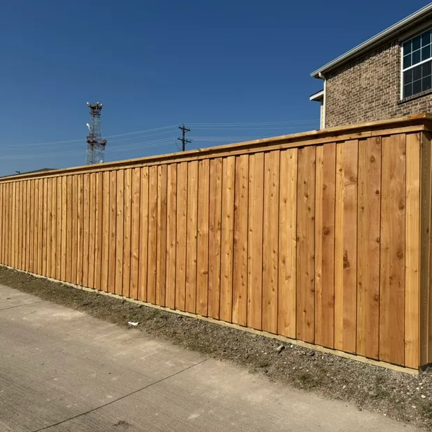 Long new cedar board-on-board privacy fence beside a brick home