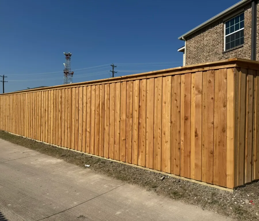 Long new cedar board-on-board privacy fence beside a brick home