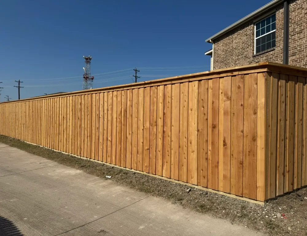 Long new cedar board-on-board privacy fence beside a brick home