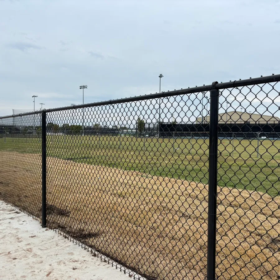Black vinyl-coated chain-link fence installed around an athletic field