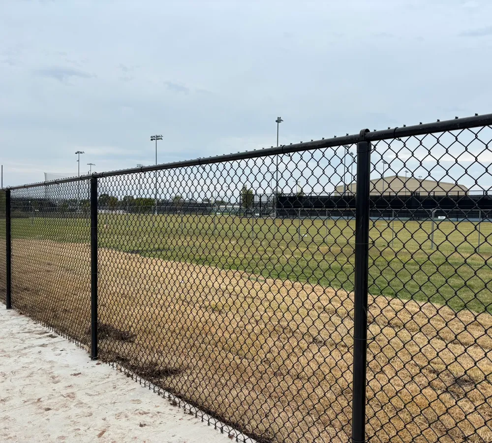 Black vinyl-coated chain-link fence installed around an athletic field