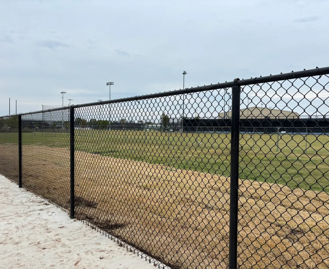 Black vinyl-coated chain-link fence installed around an athletic field