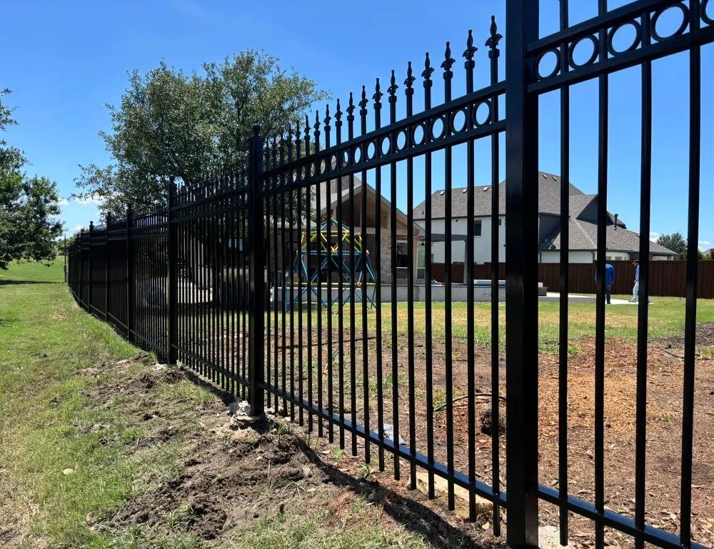 Black ornamental steel fence with spear-top pickets around a property
