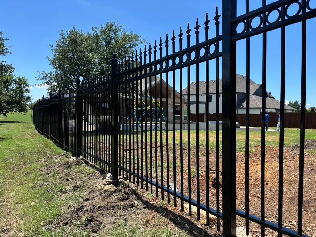 Black ornamental steel fence with spear-top pickets around a property