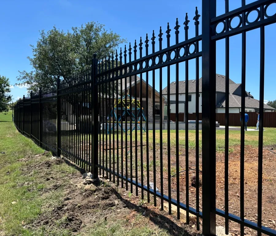 Black ornamental steel fence with spear-top pickets around a property