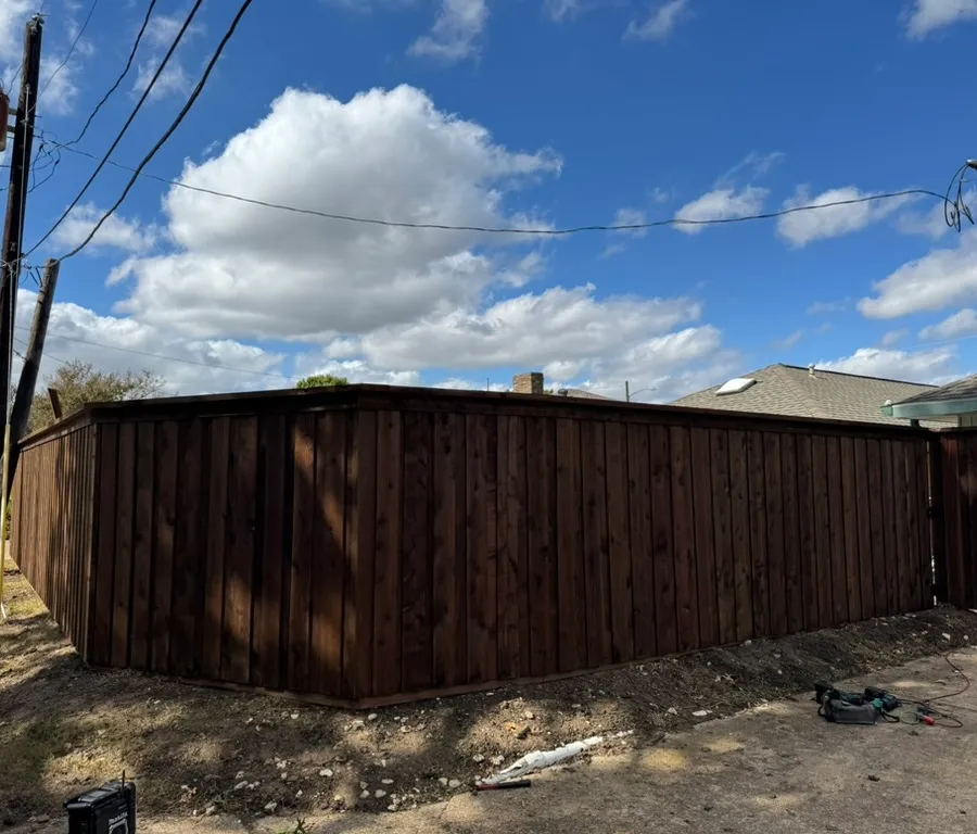 Completed dark-stained wood fence replacement along a residential alley