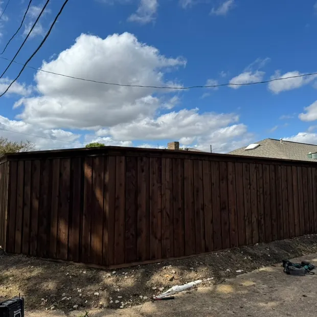 Completed dark-stained wood fence replacement along a residential alley