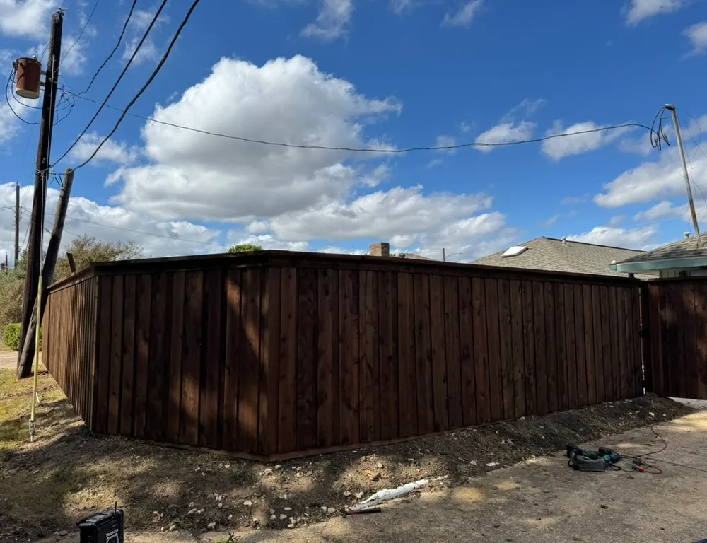 Completed dark-stained wood fence replacement along a residential alley