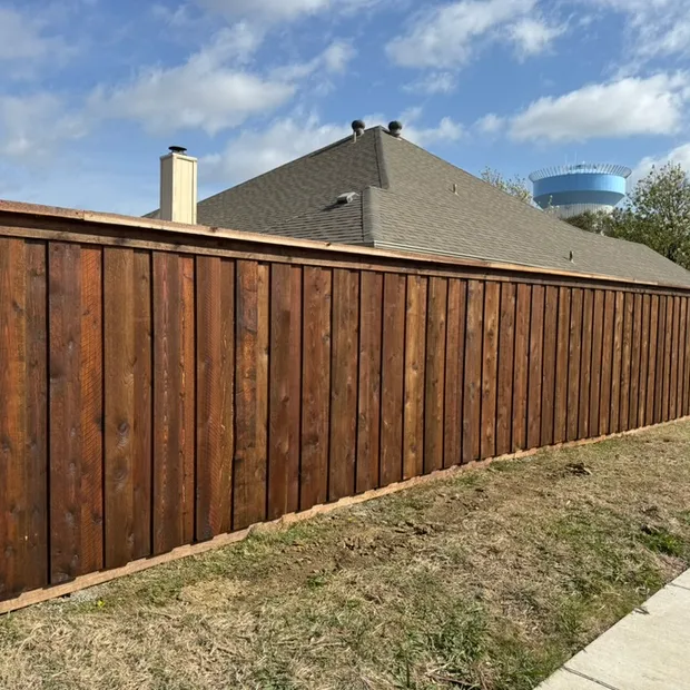 Stained board-on-board cedar privacy fence with a top cap along a Frisco sidewalk