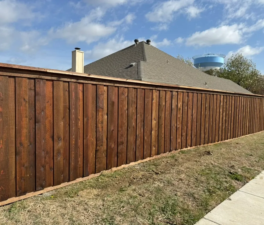 Stained board-on-board cedar privacy fence with a top cap along a Frisco sidewalk